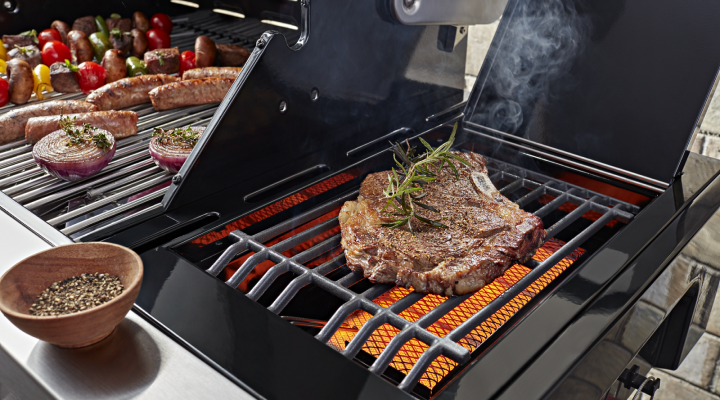 Various meats and vegetables cooking on a grill