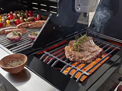 Various meats and vegetables cooking on a grill