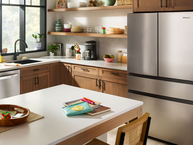  Pulled back view of a kitchen with stainless steel appliances including a refrigerator