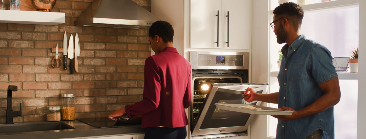 Woman and man cooking together in a kitchen with Whirlpool® small space appliances