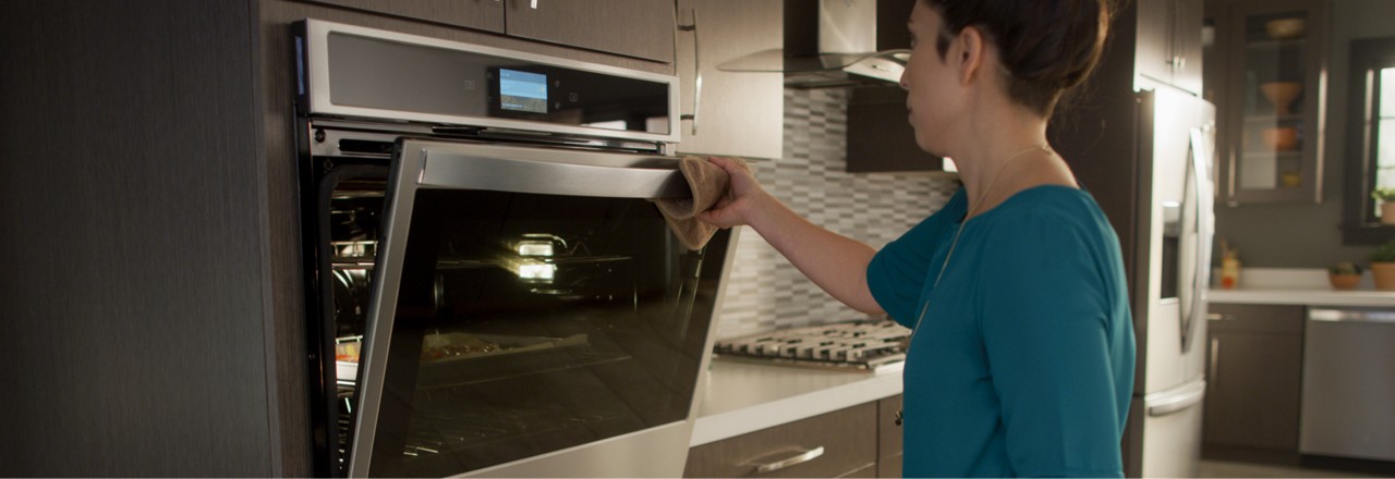 A woman opens a Whirlpool® wall oven.