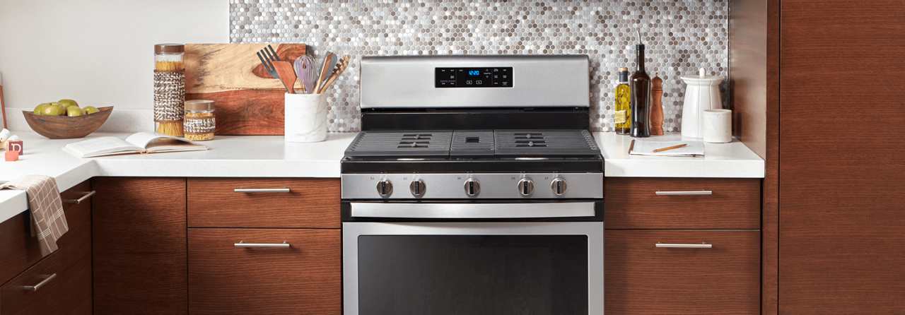 A five burner range with a stainless steel finish between two cabinets.