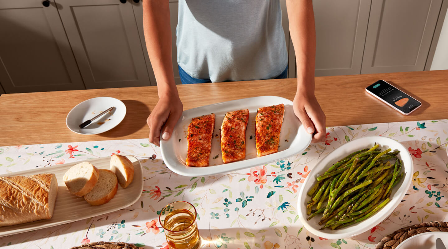 Birds-eye view of person holding platter with cooked salmon next to prepared bread and asparagus