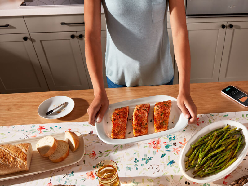 Birds-eye view of person holding platter with cooked salmon next to prepared bread and asparagus