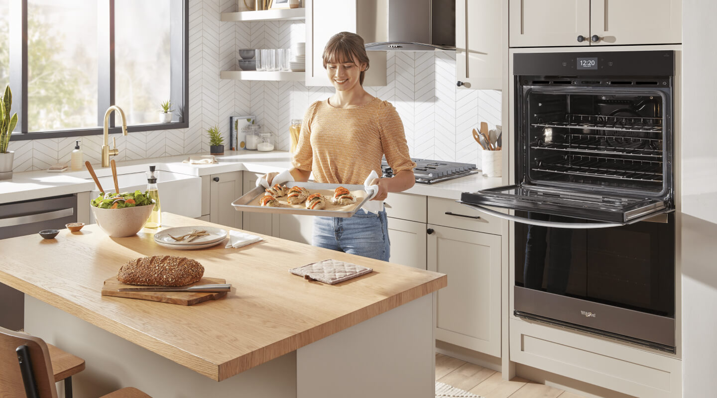 A person taking food out of the oven