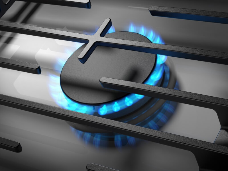 Close-up of blue flame on from a gas cooktop burner