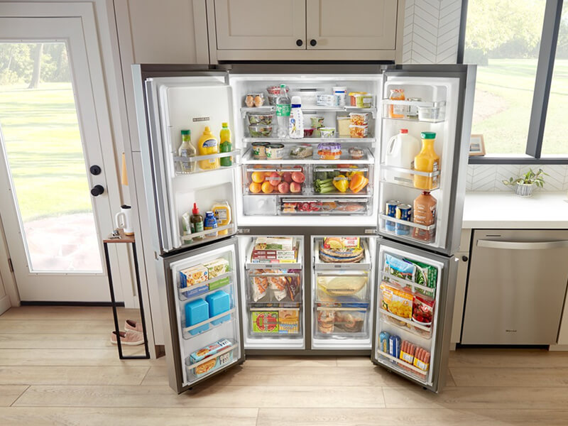 Fully stocked, open 4-door refrigerator built into tan cabinetry