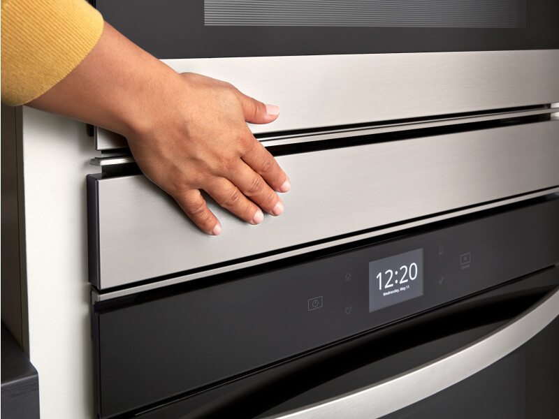 Hand closing a stainless steel wall oven