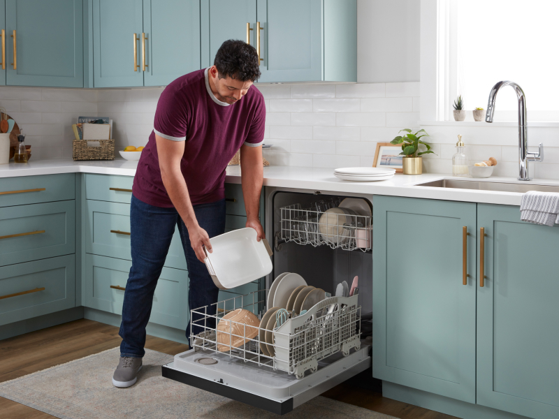 Person loading plate into dishwasher