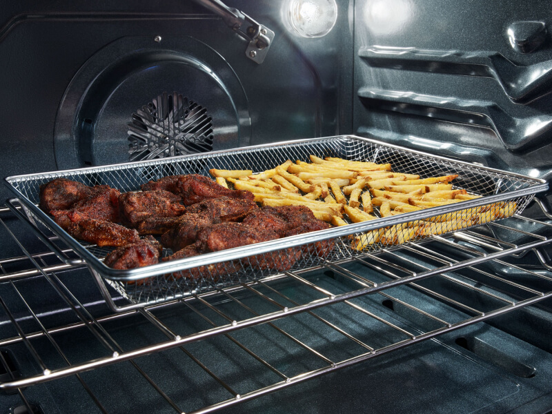 Chicken wings and fries in an air fry basket inside a Whirlpool® oven