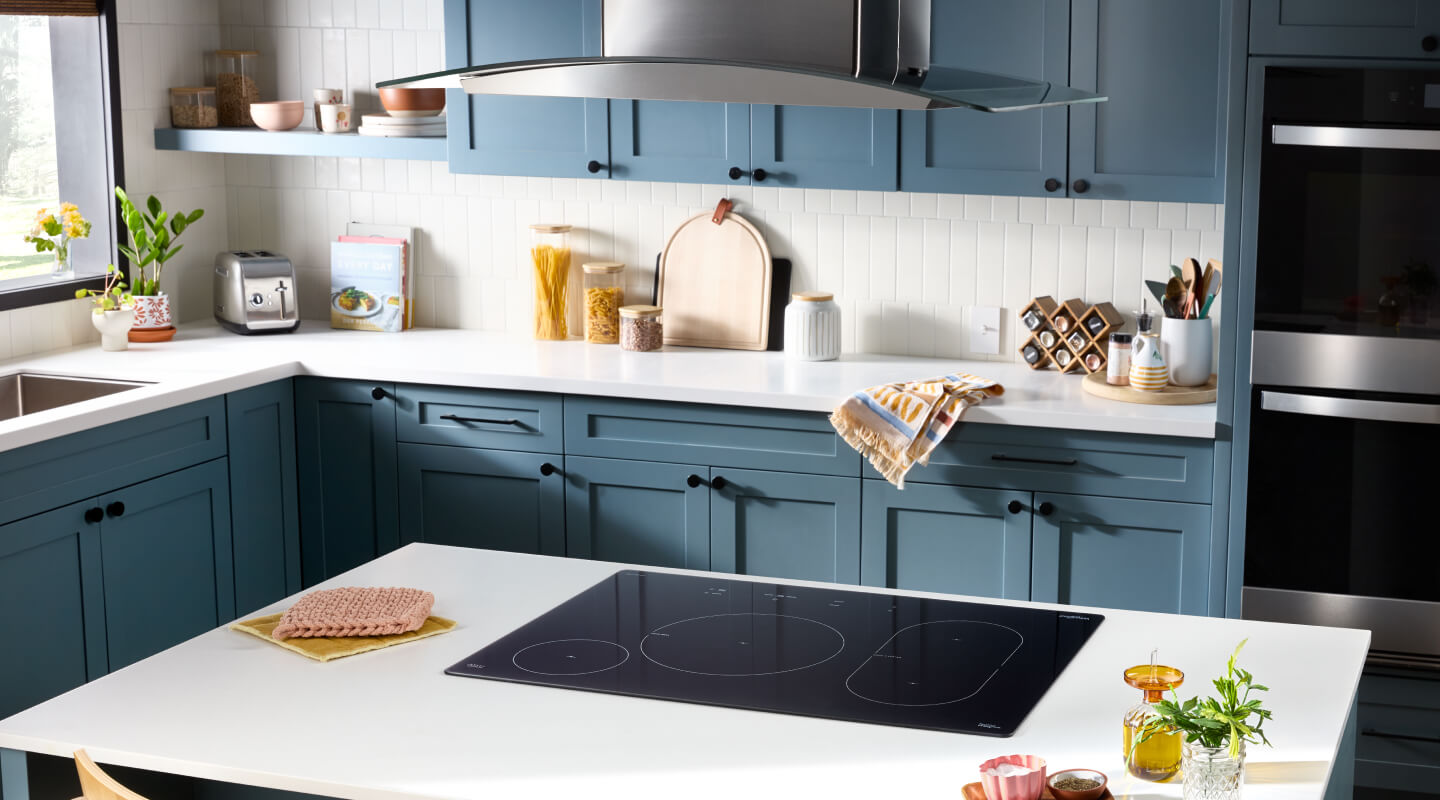  Whirlpool® Induction Cooktop in kitchen island below a stainless steel vent hood