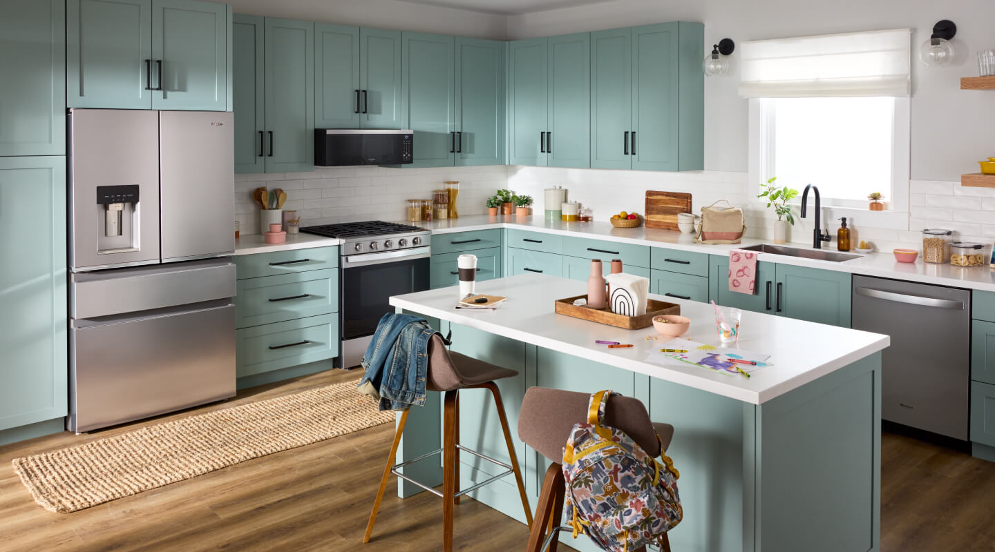 Suite of stainless steel Whirlpool® Appliances in open kitchen with light blue cabinetry