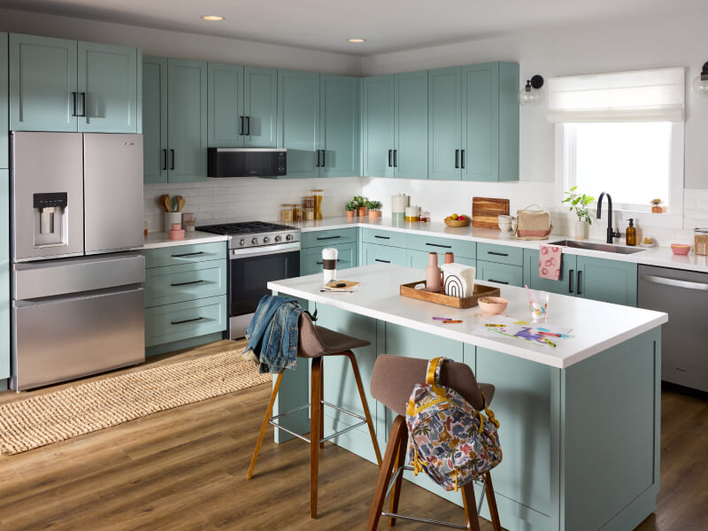 Suite of stainless steel Whirlpool® Appliances in open kitchen with light blue cabinetry