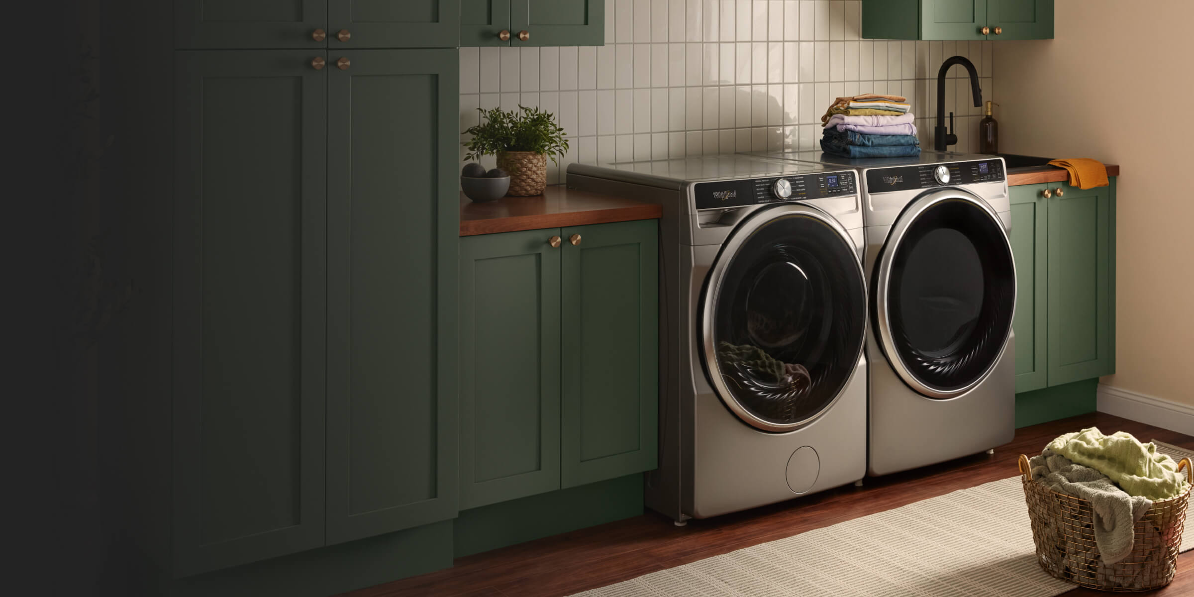 Silver front load Whirlpool® Washer and Dryer set in green cabinetry