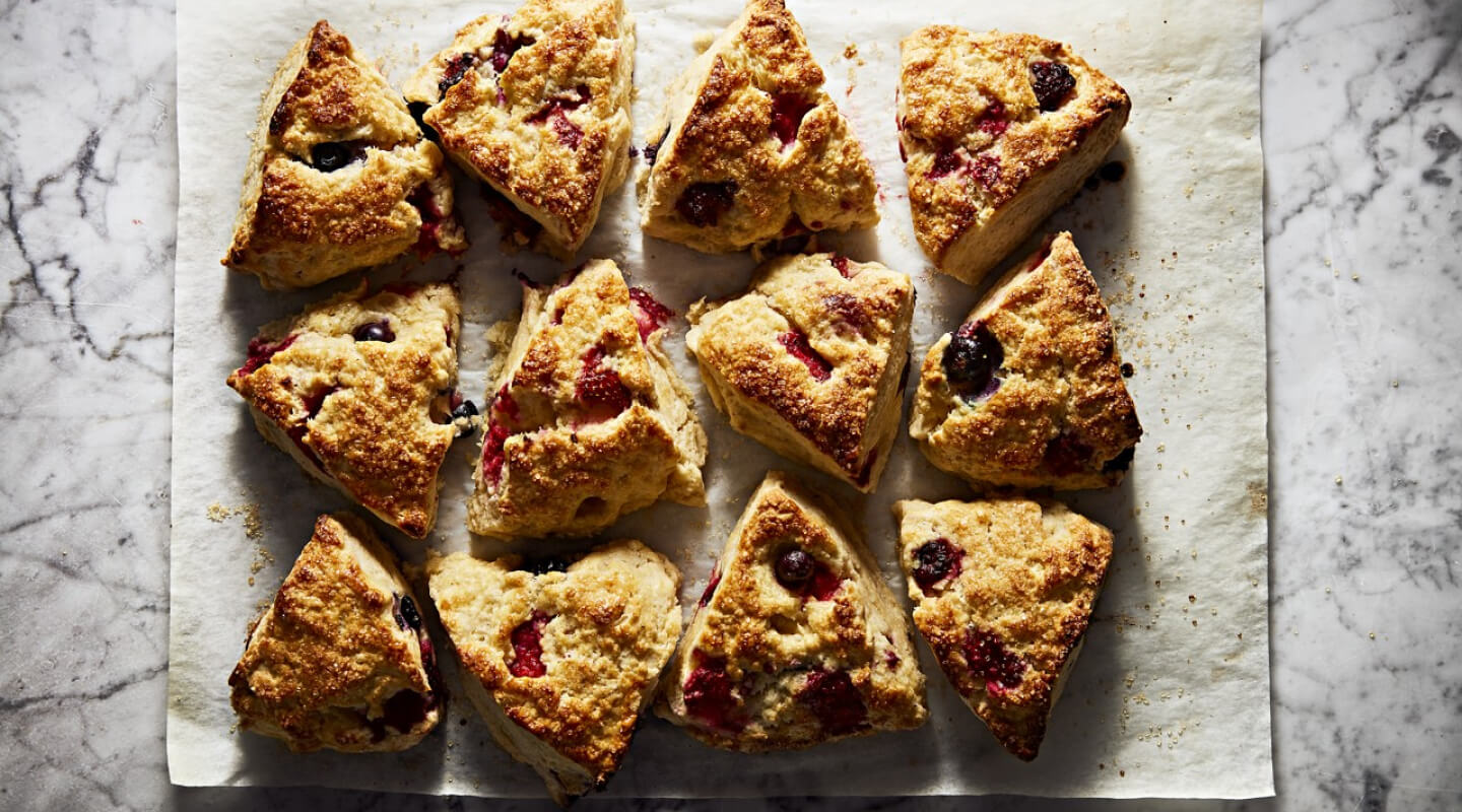A batch of fresh scones resting on parchment paper