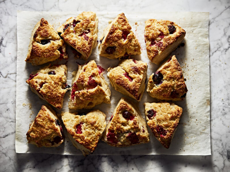 A batch of fresh scones resting on parchment paper