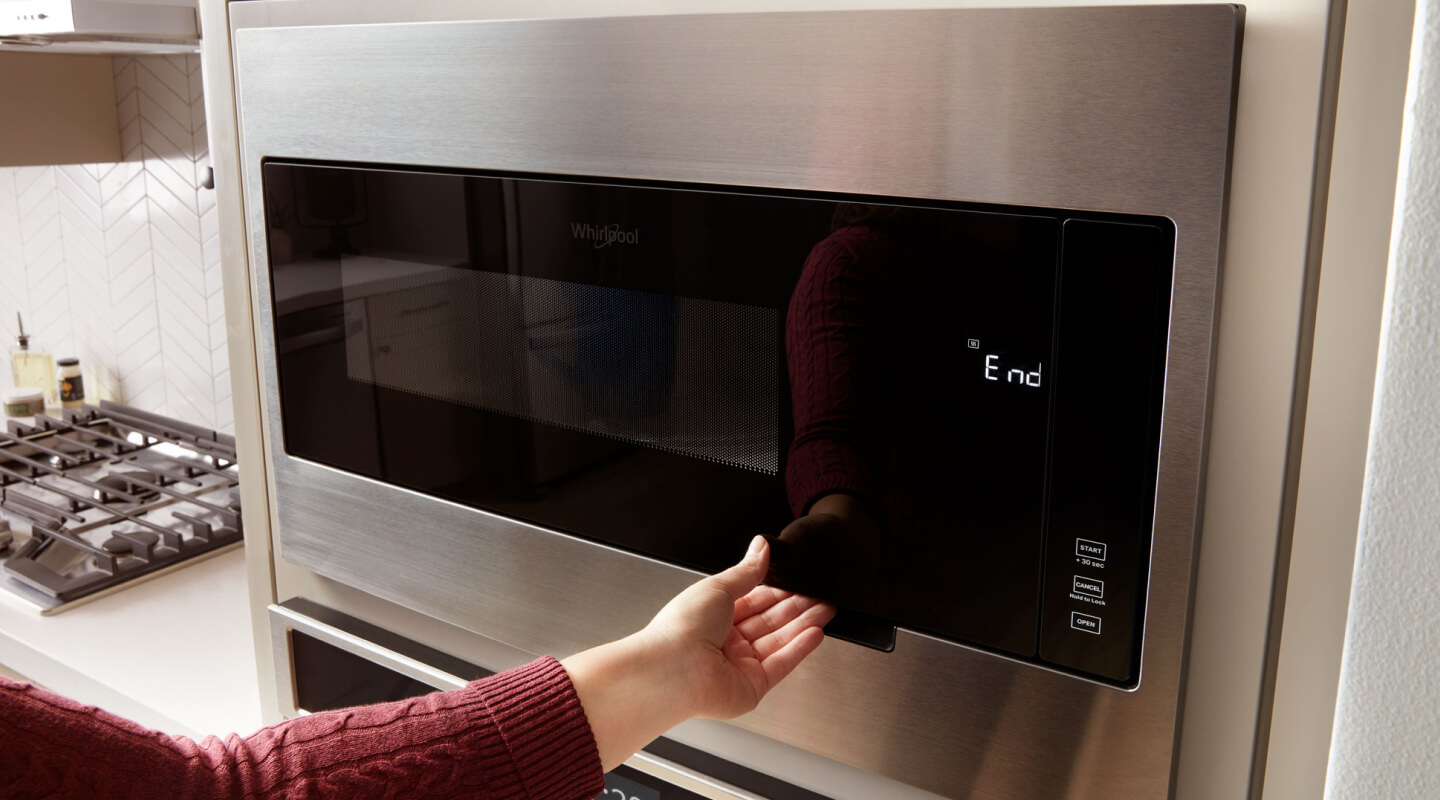 Person opening a Whirlpool® microwave