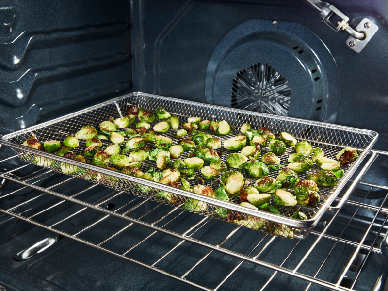 Vegetables in an air fryer basket in an oven