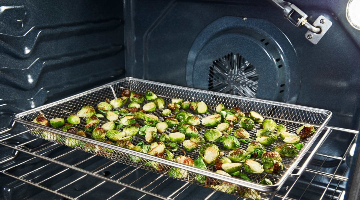 Vegetables in an air fryer basket in an oven