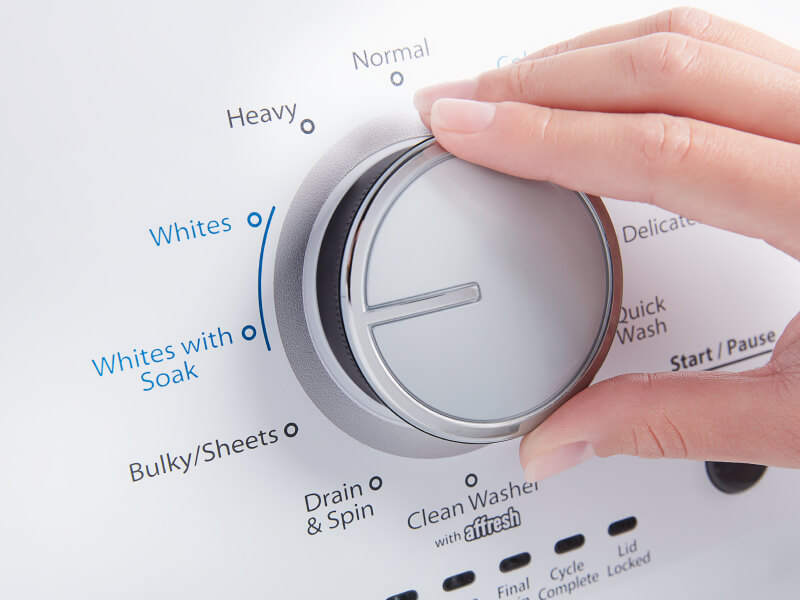 A person adjusting the settings of a washer