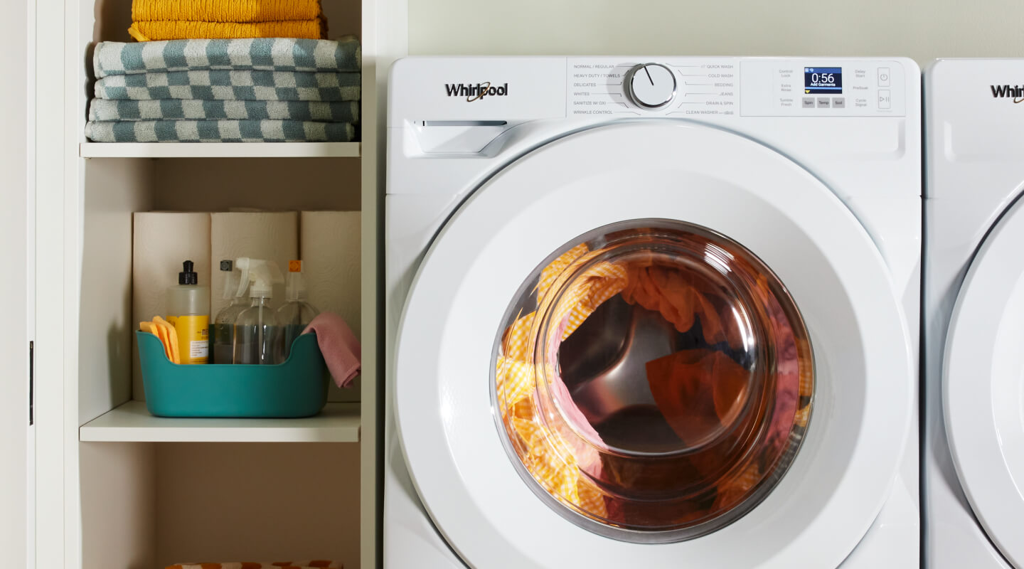 A laundry supply cabinet next to a white washer