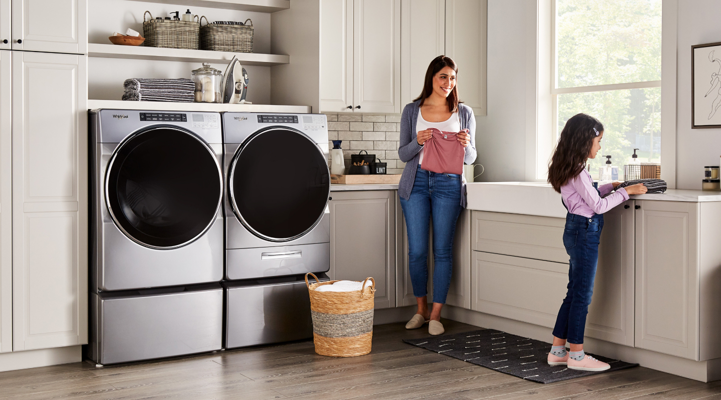 Child and adult doing laundry in a laundry room