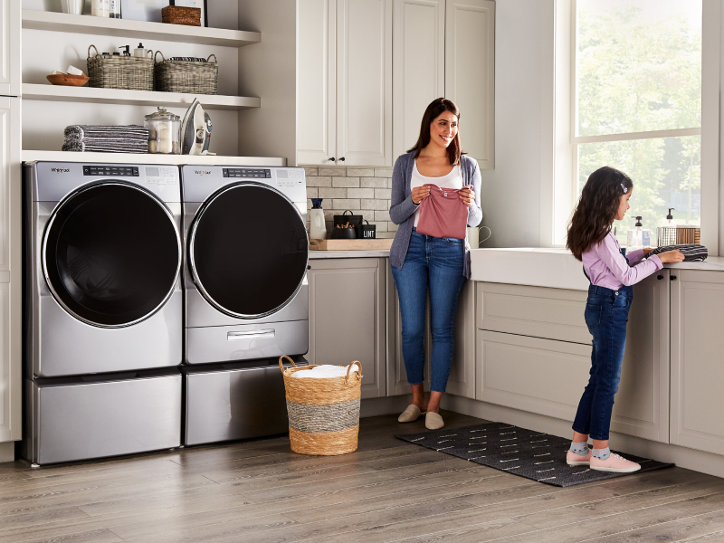 Child and adult doing laundry in a laundry room