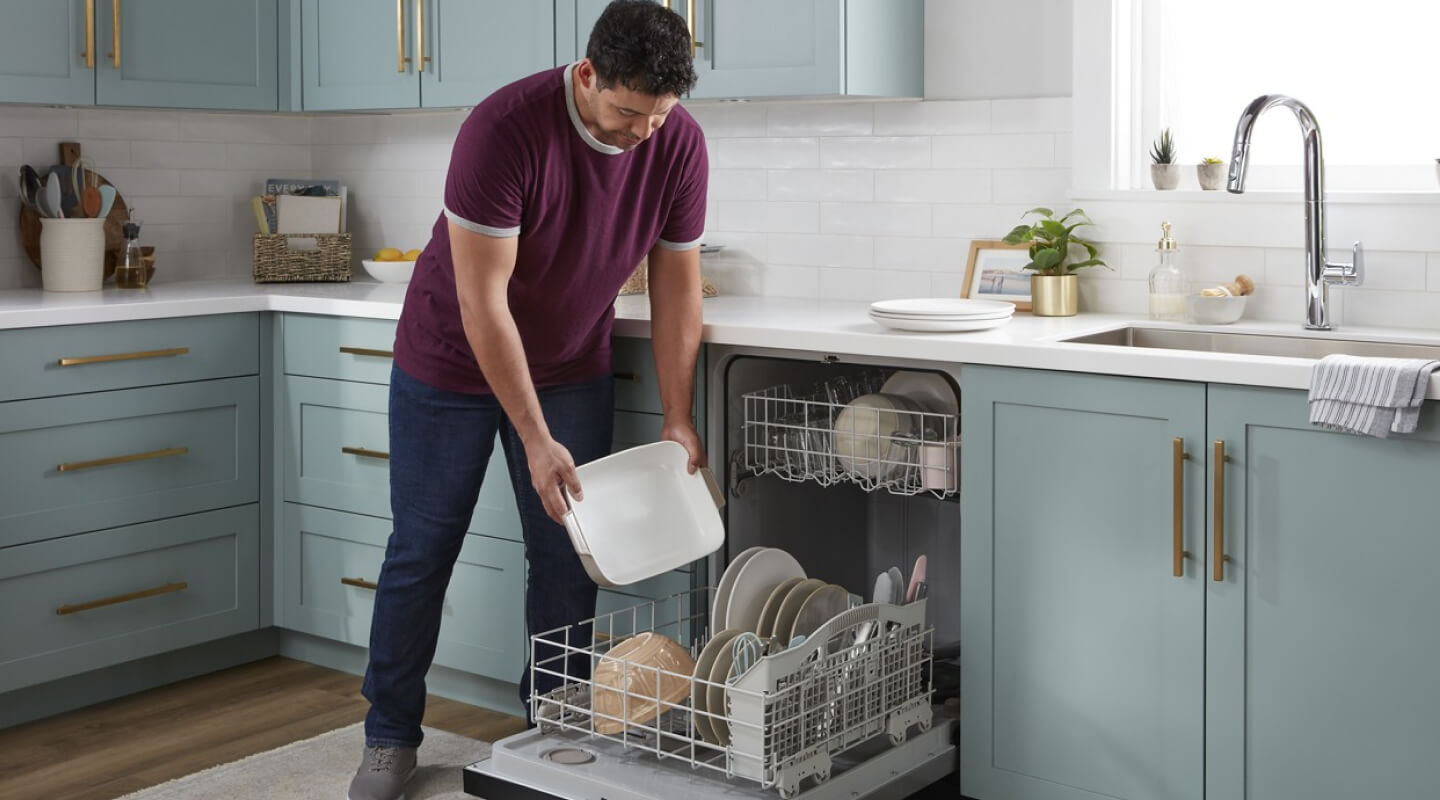 A person loading a Whirlpool® Dishwasher in a modern kitchen