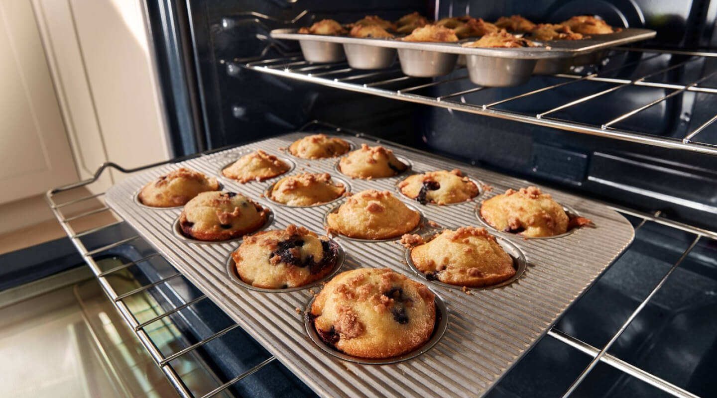 Muffins cooking in pans on two different oven racks