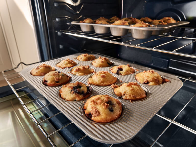 Muffins cooking in pans on two different oven racks