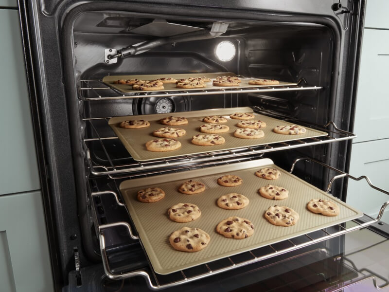 Three trays of cookies baking in an oven