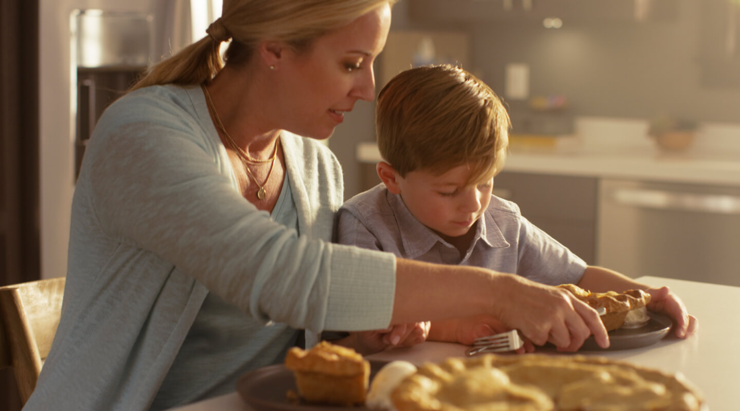 A mom serving her son a slice of pie