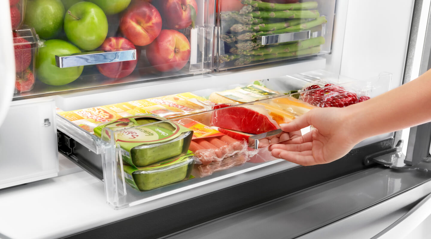 A person pulling out a fridge drawer