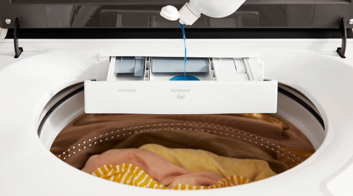 Person adding detergent to a washing machine