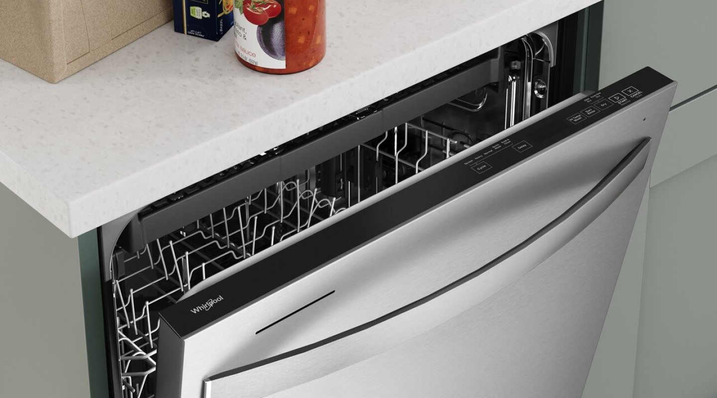 Close-up of top of open dishwasher door beneath white cabinetry. 
