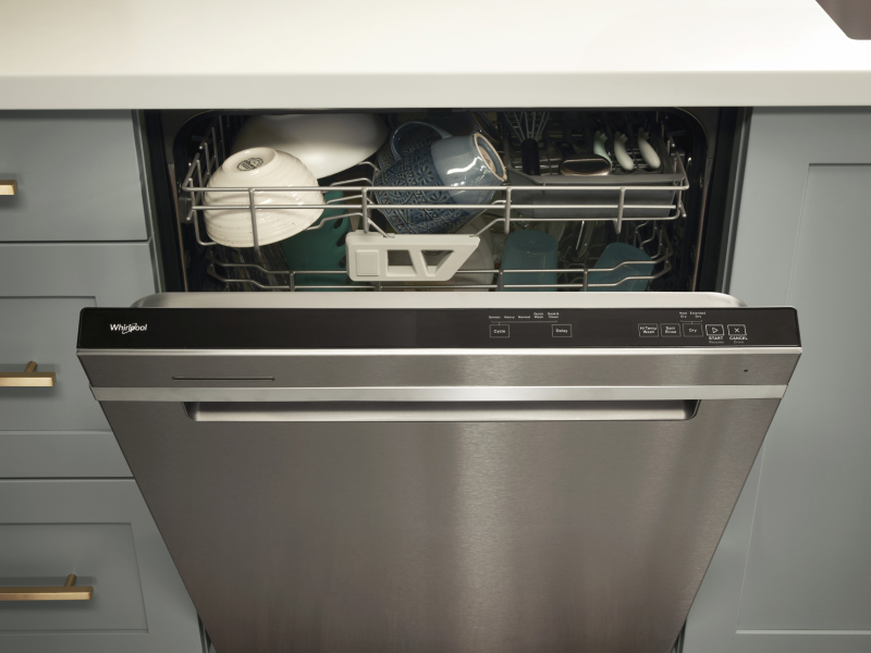 A loaded Whirlpool® dishwasher with an open door