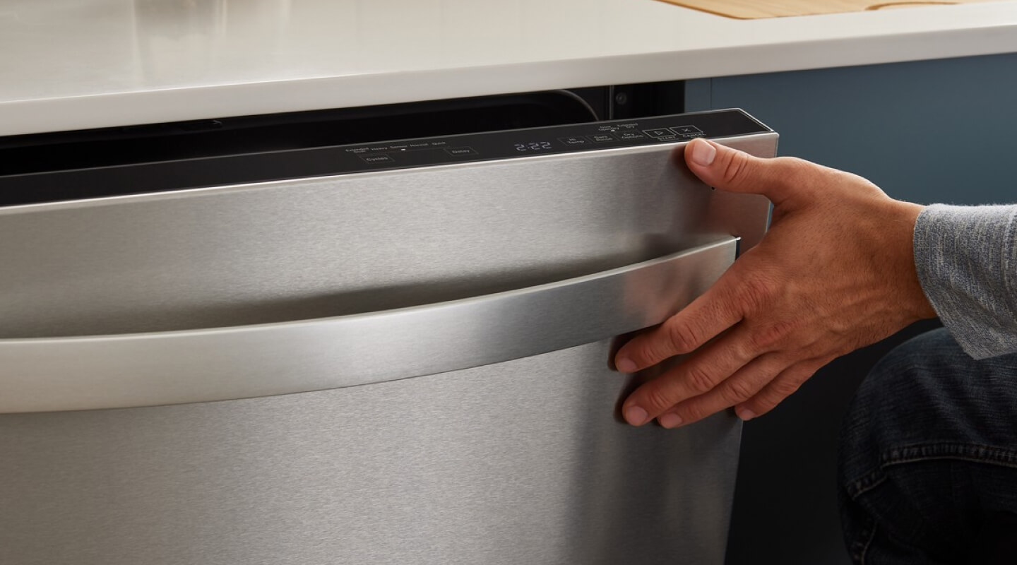 A person closing the door of a dishwasher