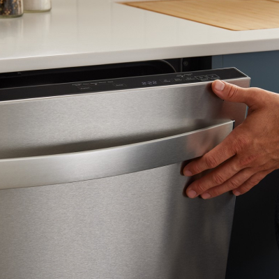 A person closing the door of a dishwasher
