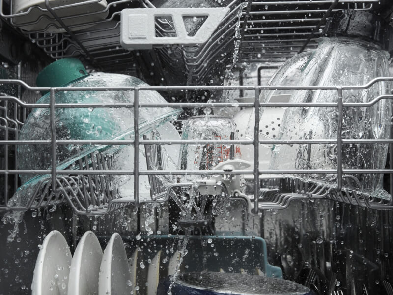 Dishes being rinsed with water inside a dishwasher