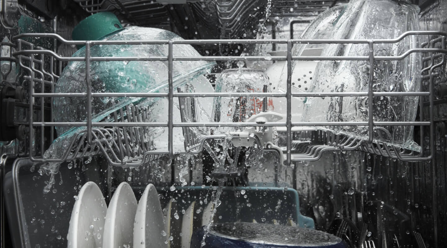 Dishes being rinsed with water inside a dishwasher