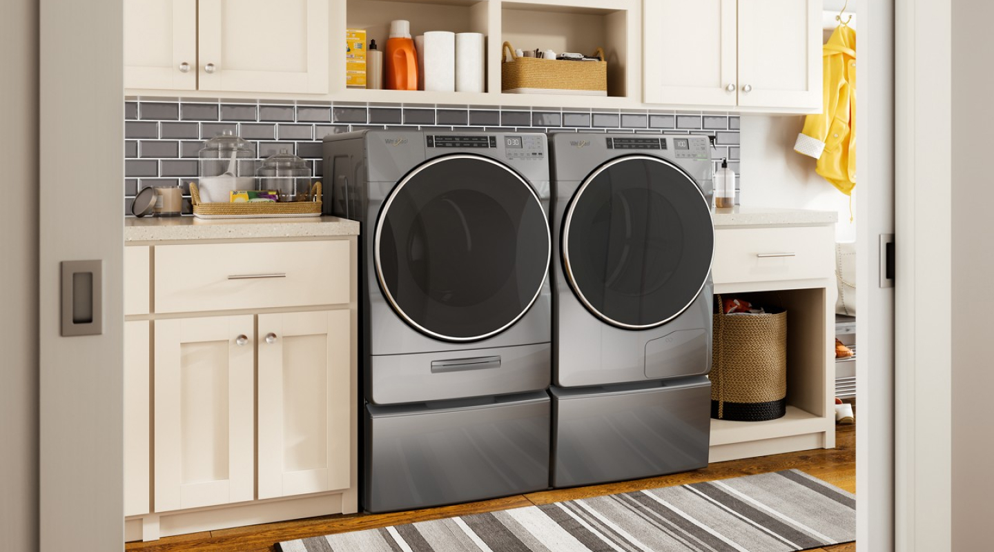 Front load Whirlpool® Washer and Dryer pair on pedestals in a laundry room