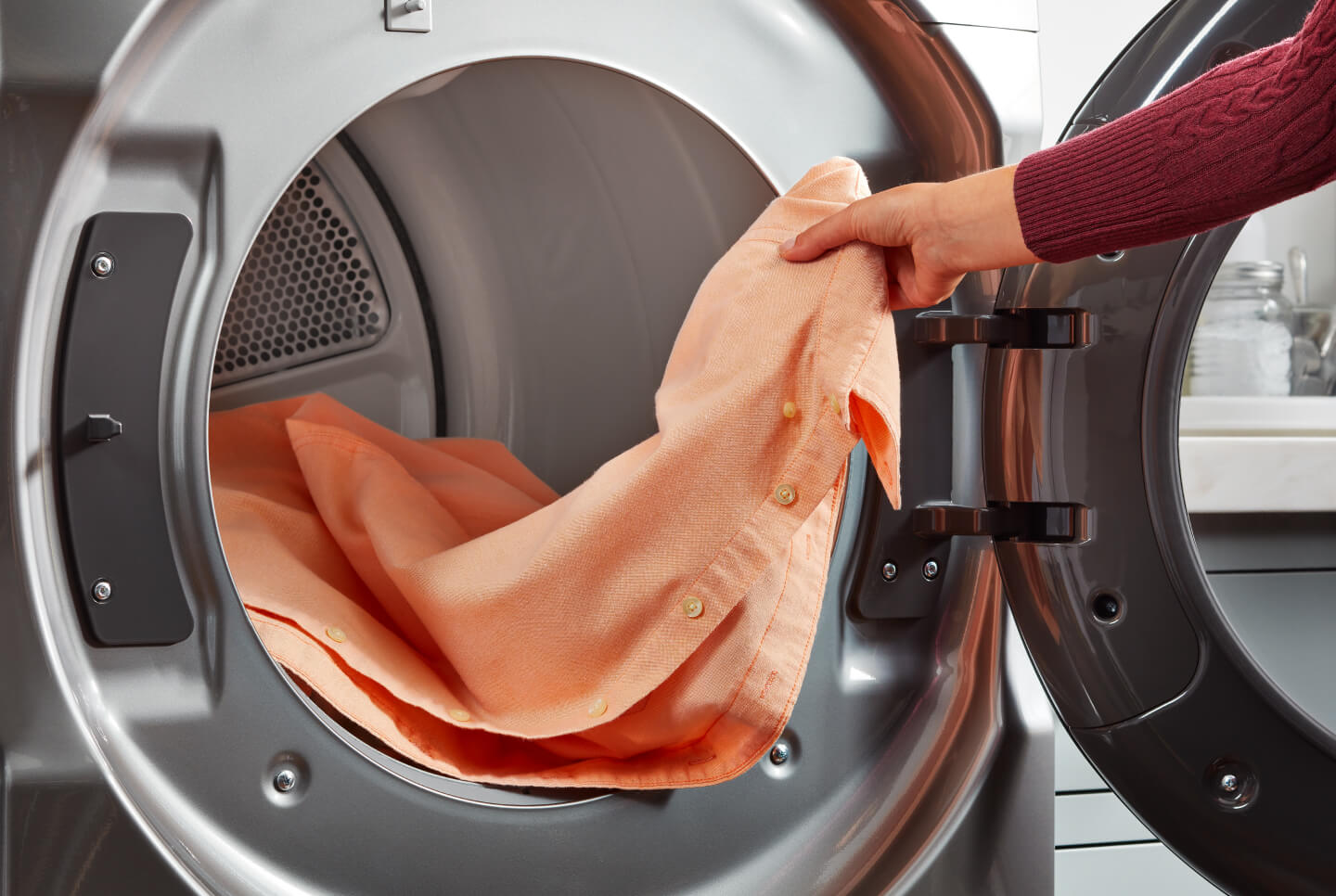 Person loading shirt in dryer