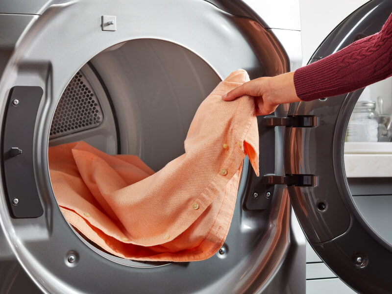 Person loading shirt in dryer