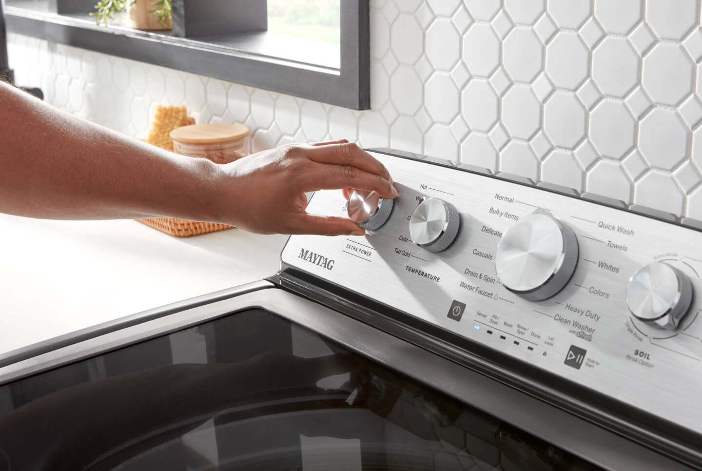 Person turning knob on washing machine