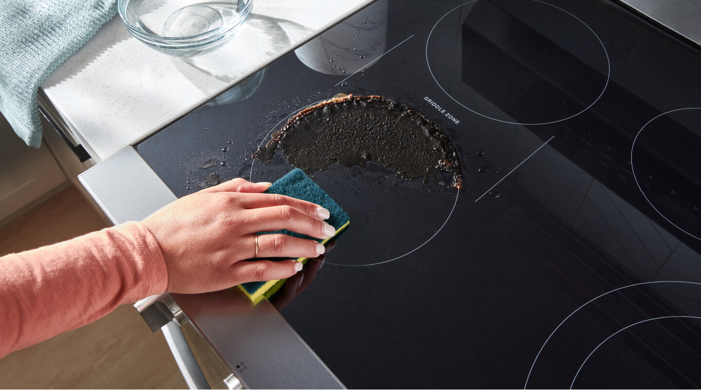Person cleaning a spill on an electric cooktop