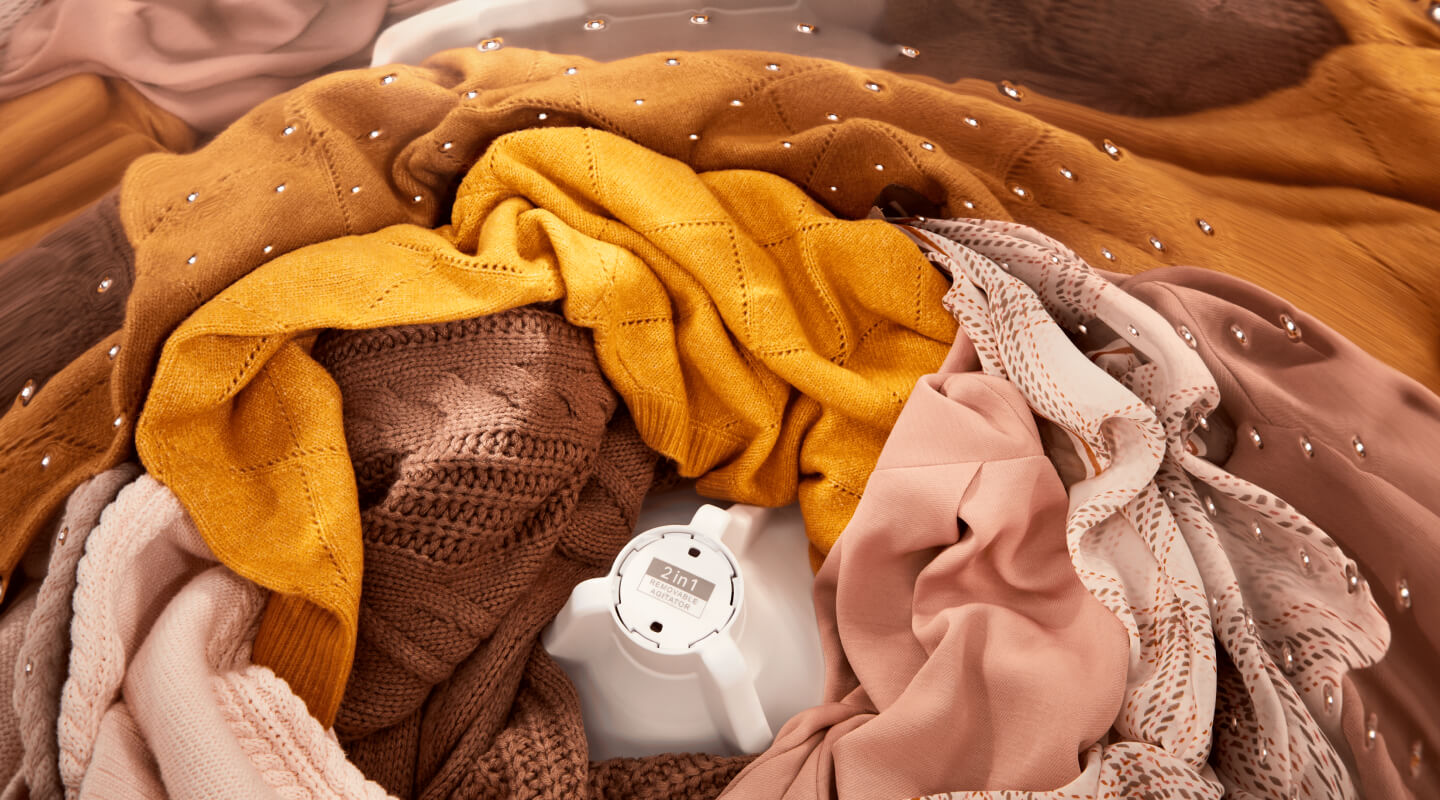 Orange- and pink-toned clothes inside of a Whirlpool® Washer with the 2 in 1 Removable Agitator
