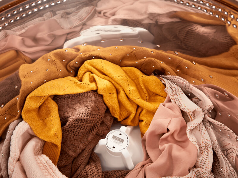 Orange- and pink-toned clothes inside of a Whirlpool® Washer with the 2 in 1 Removable Agitator
