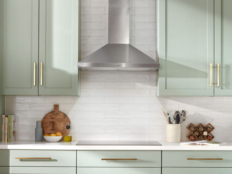 A stainless steel range hood above a cooktop 