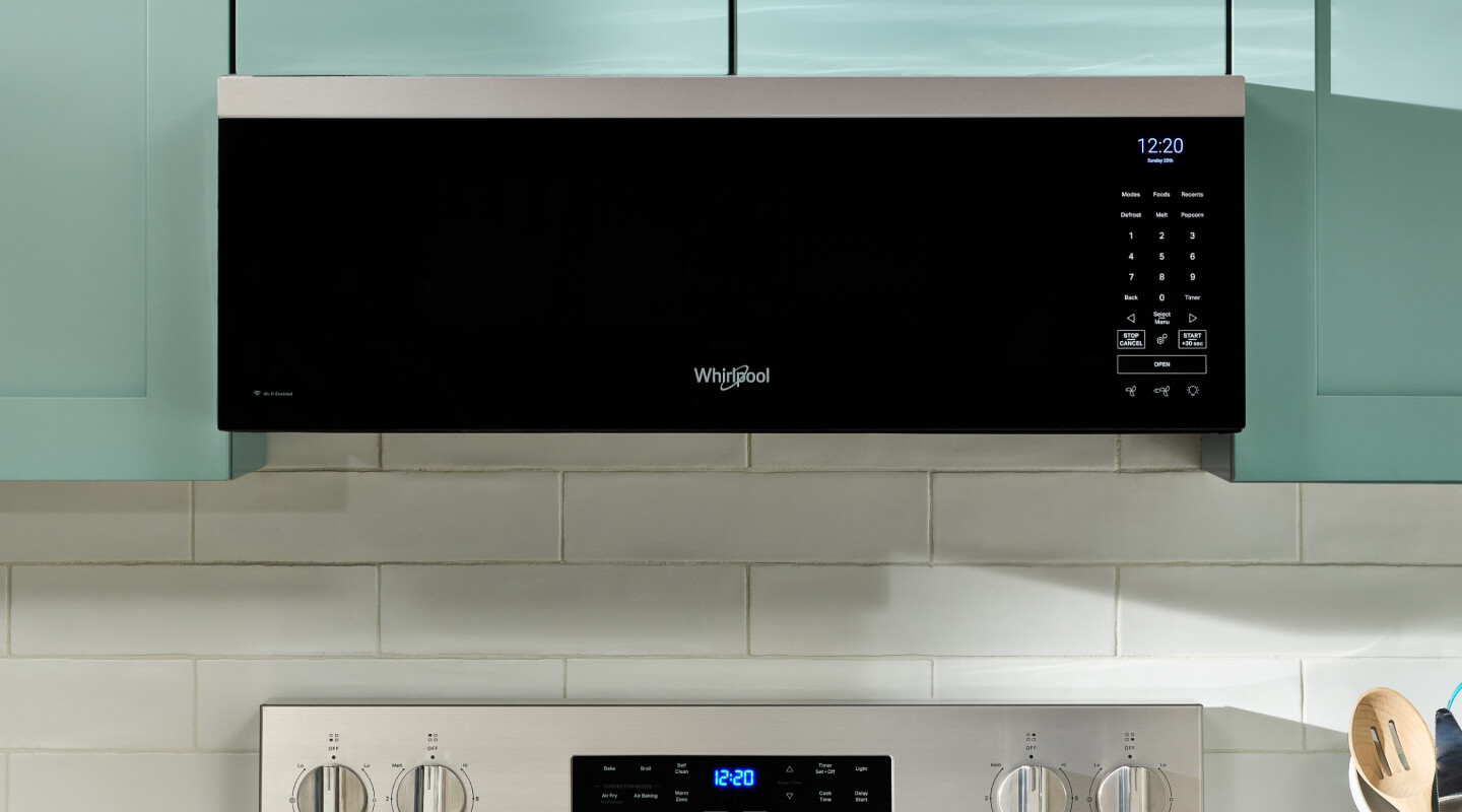 A Whirlpool® low profile microwave installed against modern, light green cabinets