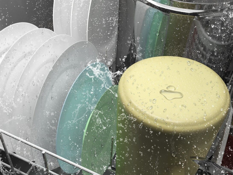 A closeup of the bottom rack of a Whirlpool® dishwasher washing dishware during a wash cycle.